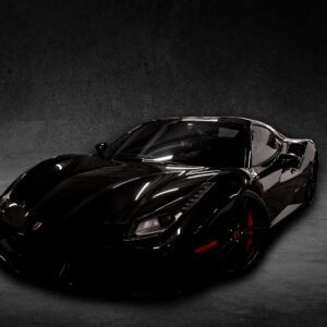 A black sports car is parked in the dark.