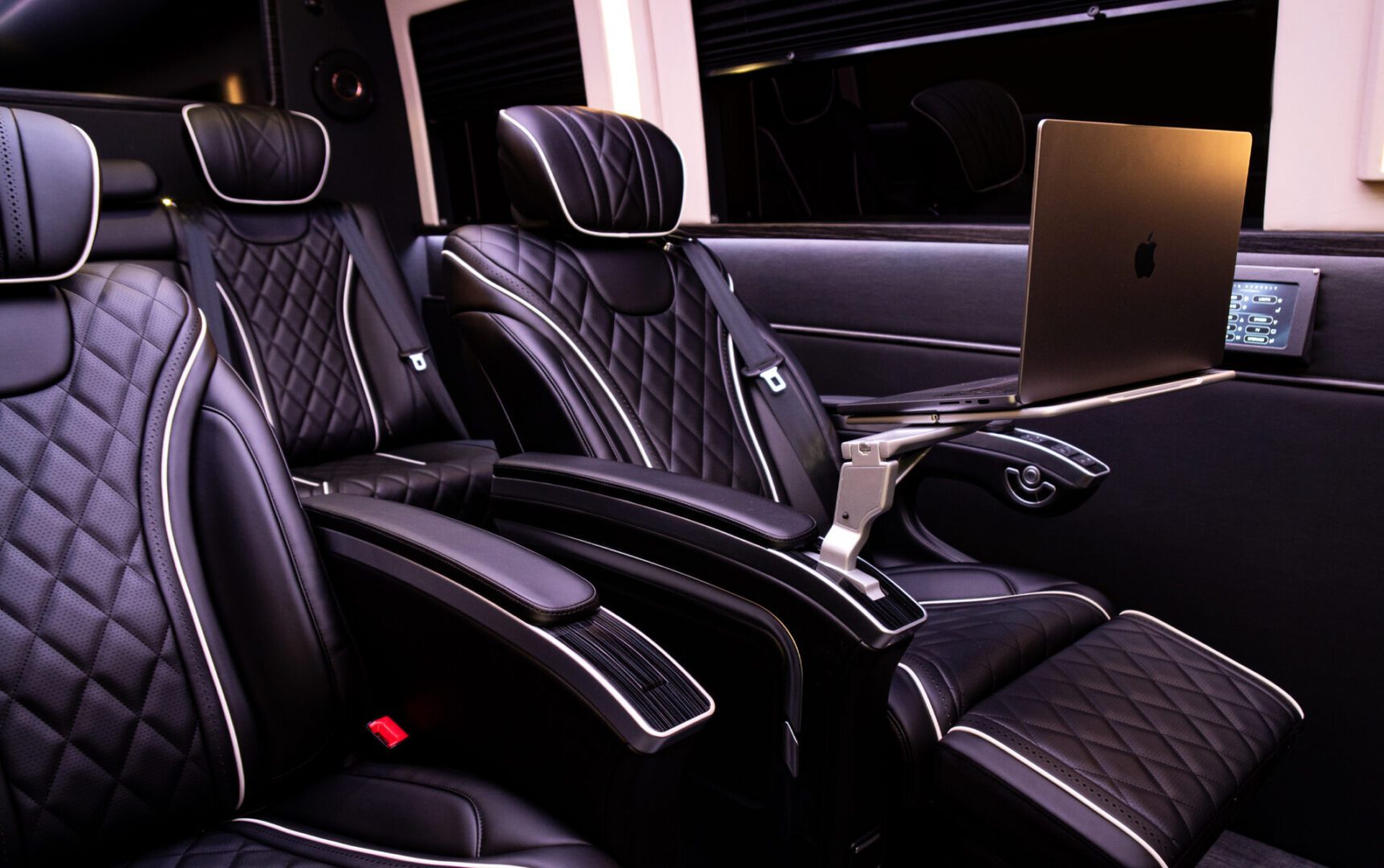 A black leather car with two seats and a laptop